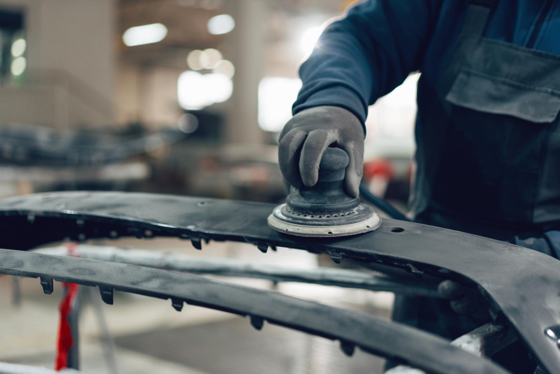 A technician sands a metal frame